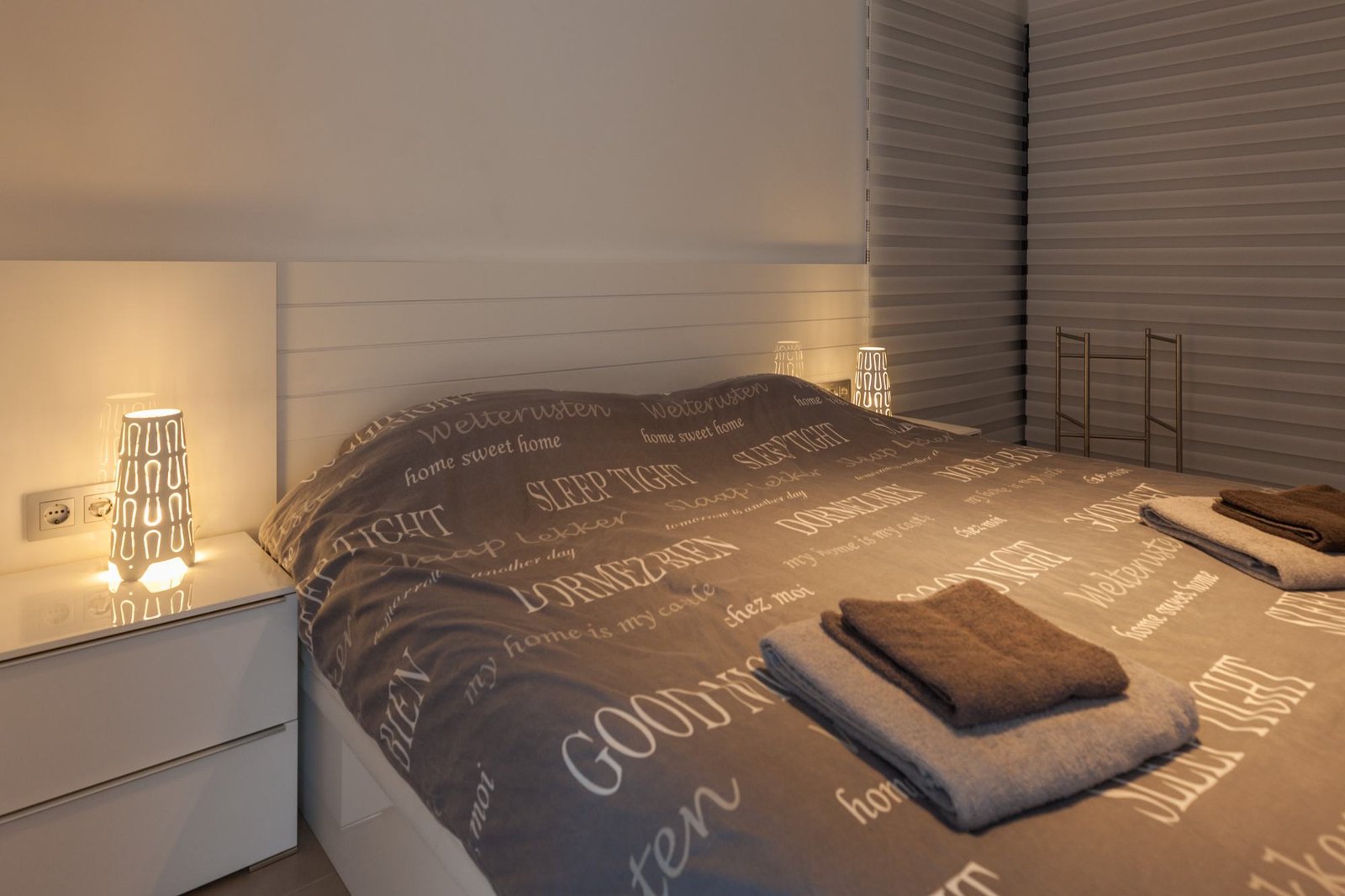 Slaapkamer in avondsfeer met handdoeken op het bed